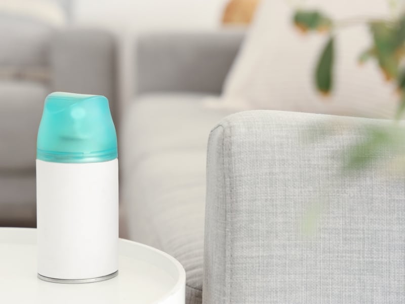 Compact Commercial Room Air Fresheners dispenser on white table near grey sofa.