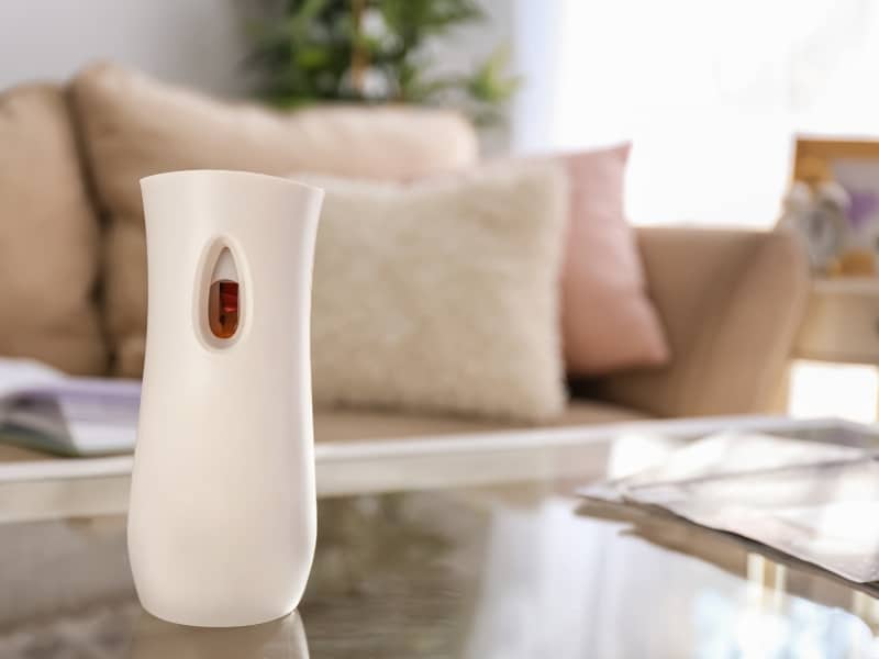 Automatic air freshener refill dispenser placed on coffee table in cosy living room.